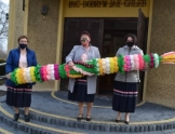 Trzy kobiety w maseczkach trzymają dużą palme